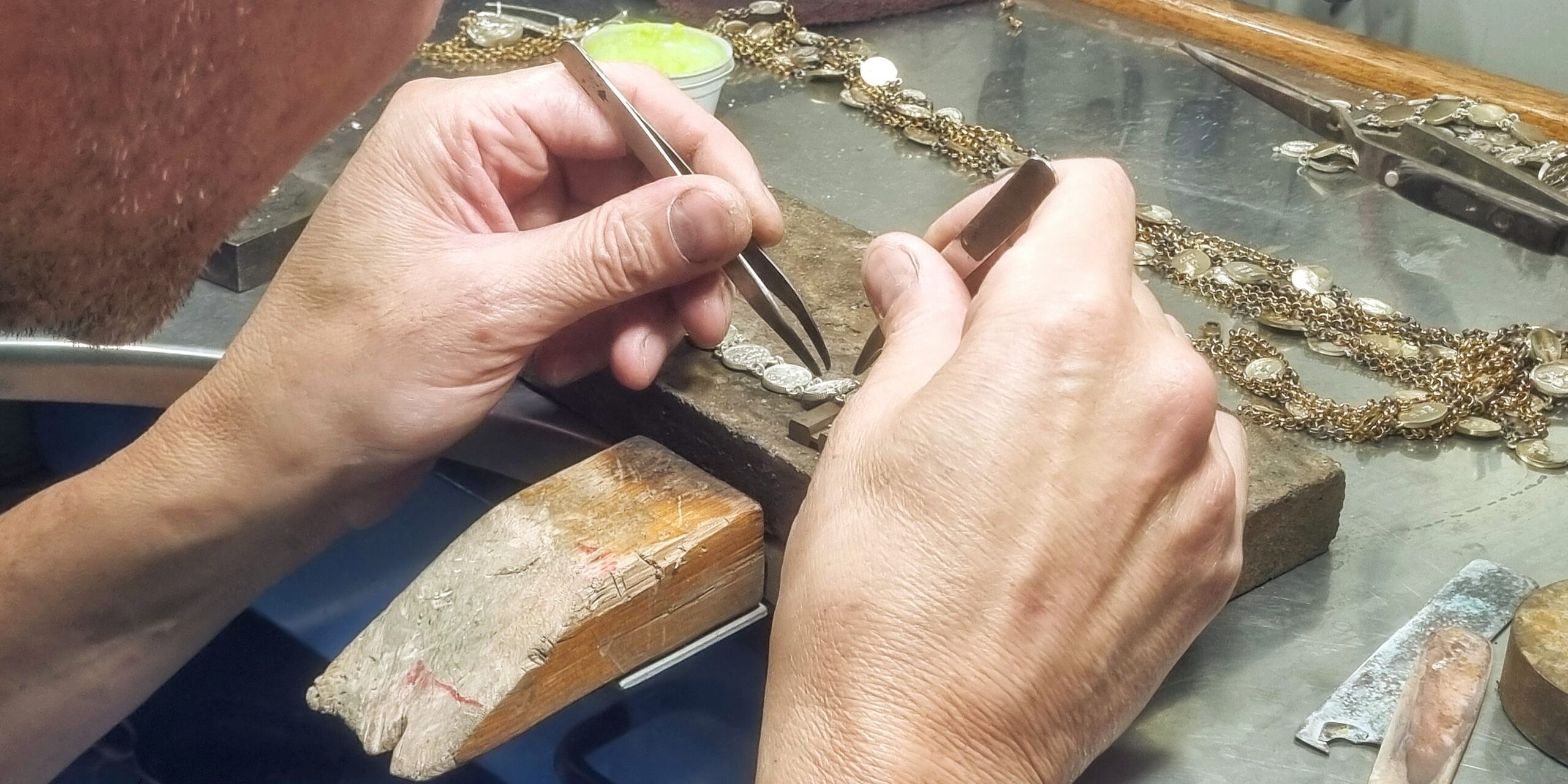 Ourives montando peça de joalheria em bancada de acabamento